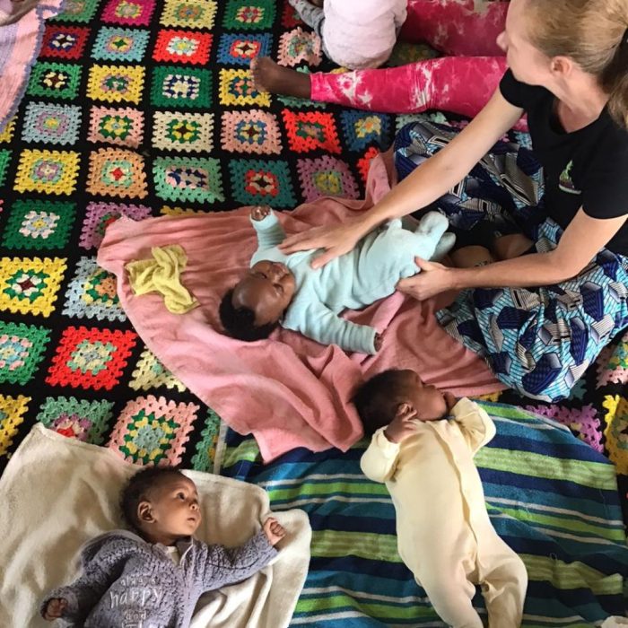 Image of Monja Boonzaier (NGO Founder) and three babies on blankets during a support session / skills-development workshop to improve caregiver wellbeing, responsive parenting skills and early childhood development. 